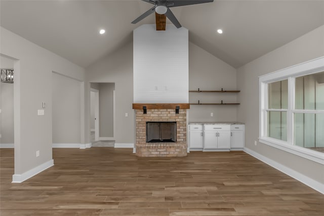 unfurnished living room featuring ceiling fan, light hardwood / wood-style flooring, a fireplace, and high vaulted ceiling