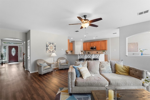 living room featuring ceiling fan and dark wood-type flooring