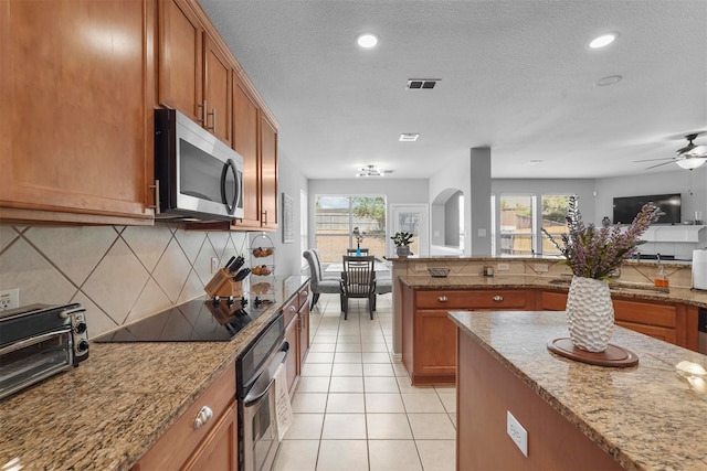 kitchen featuring light stone countertops, stainless steel appliances, a textured ceiling, and light tile patterned floors