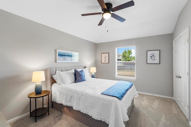 carpeted bedroom with a closet, lofted ceiling, and ceiling fan