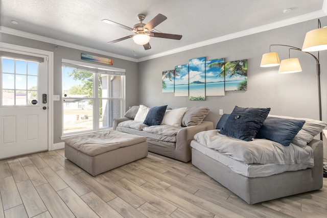 living room with light wood-type flooring, ceiling fan, a textured ceiling, and crown molding