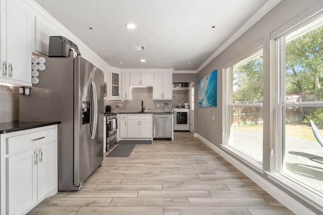 kitchen with sink, light hardwood / wood-style flooring, white cabinetry, appliances with stainless steel finishes, and decorative backsplash