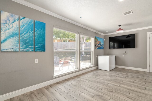 unfurnished living room featuring ornamental molding, light hardwood / wood-style floors, and a textured ceiling