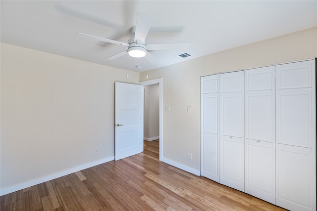 unfurnished bedroom featuring ceiling fan, a closet, and light wood-type flooring