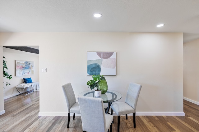 dining space with hardwood / wood-style flooring and vaulted ceiling