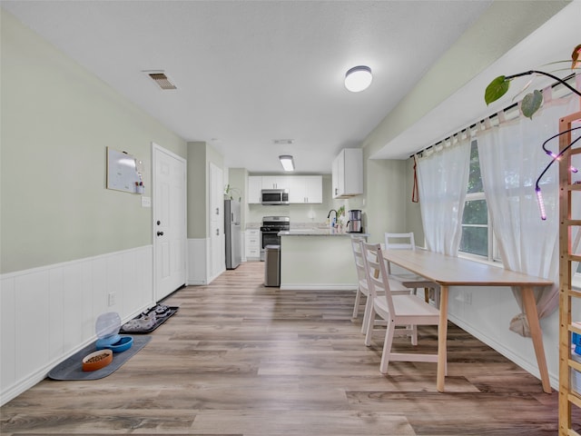 kitchen with appliances with stainless steel finishes, light hardwood / wood-style floors, sink, and white cabinets