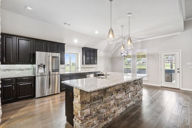 kitchen with plenty of natural light, light stone counters, an island with sink, and appliances with stainless steel finishes