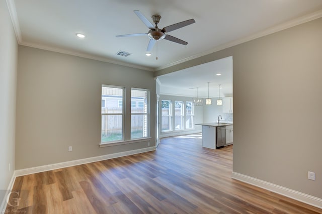 unfurnished living room with sink, light hardwood / wood-style floors, ceiling fan with notable chandelier, and ornamental molding