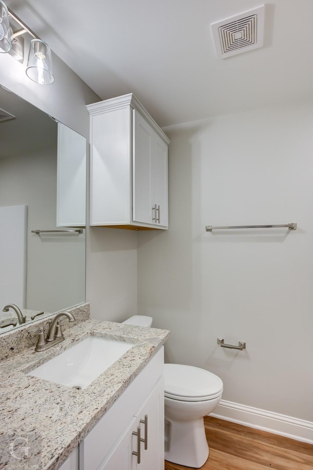 bathroom with hardwood / wood-style floors, vanity, and toilet