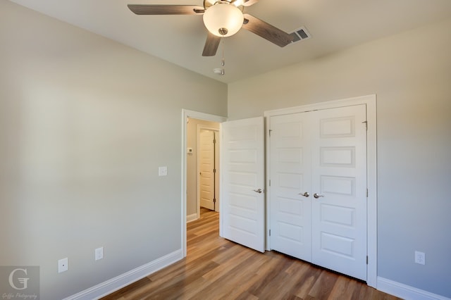 unfurnished bedroom featuring hardwood / wood-style floors, a closet, and ceiling fan