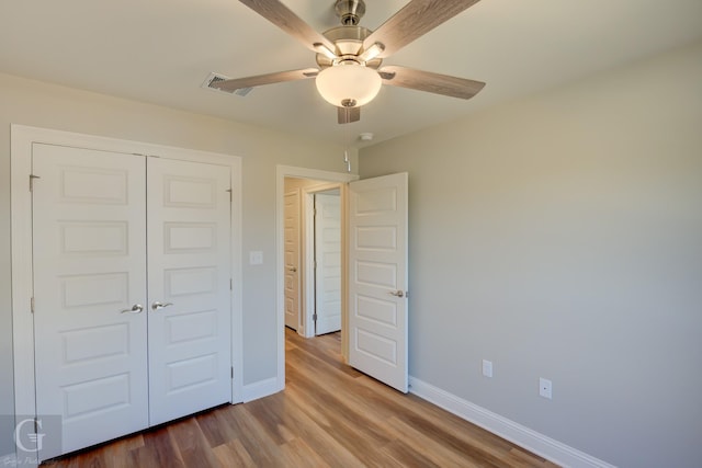 unfurnished bedroom with ceiling fan, wood-type flooring, and a closet