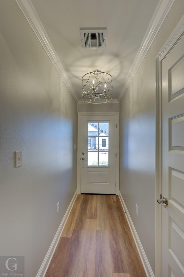 doorway to outside featuring hardwood / wood-style floors, a notable chandelier, and crown molding