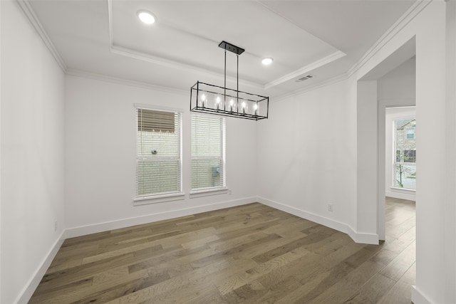 unfurnished dining area featuring a notable chandelier, dark hardwood / wood-style floors, ornamental molding, and a tray ceiling