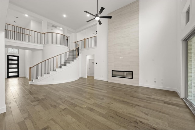 1406 Chickadee Dr, Mansfield, TX 76063 - unfurnished living room featuring a high ceiling, stairs, ceiling fan, wood finished floors, and a tiled fireplace