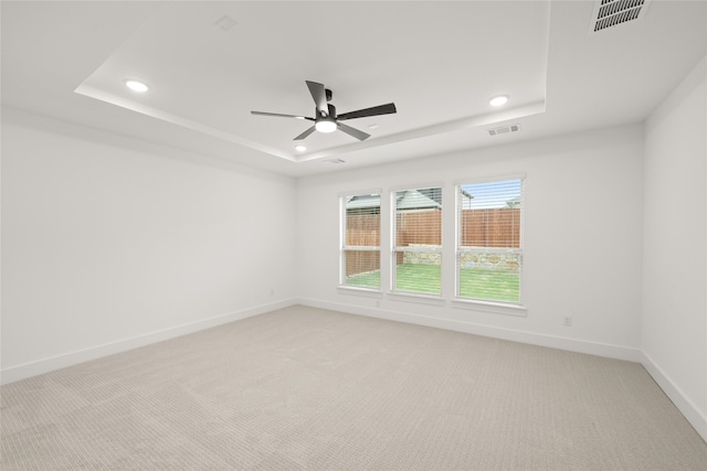 carpeted spare room featuring ceiling fan and a tray ceiling