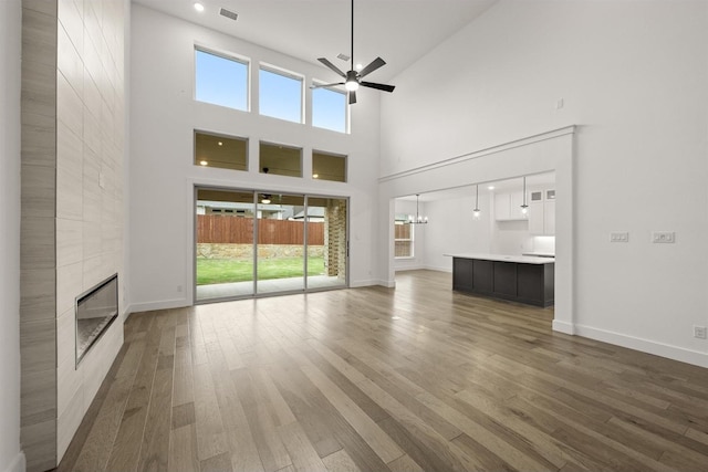 1406 Chickadee Dr, Mansfield, TX 76063 - unfurnished living room with a tile fireplace, ceiling fan, a high ceiling, wood finished floors, and recessed lighting