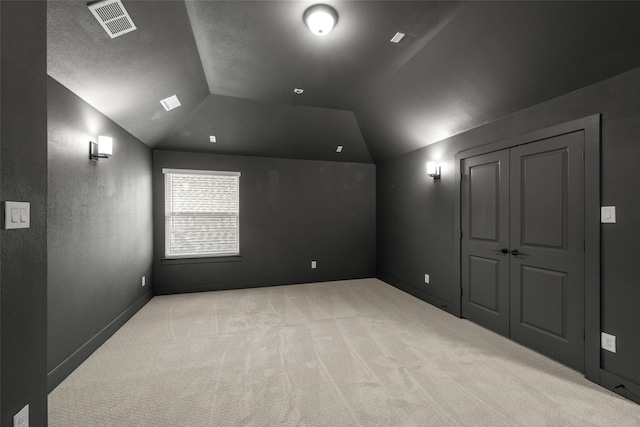 additional living space with light colored carpet and vaulted ceiling