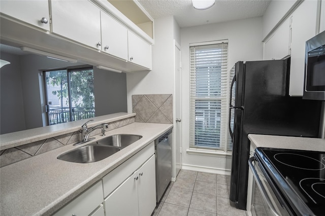 kitchen with sink, light tile patterned floors, a textured ceiling, white cabinetry, and stainless steel appliances