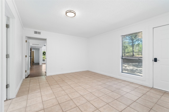 unfurnished room featuring a textured ceiling, light tile patterned floors, and crown molding