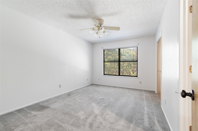 spare room featuring ceiling fan, light colored carpet, and a textured ceiling