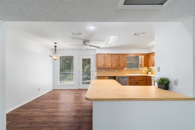 kitchen with dishwasher, sink, kitchen peninsula, decorative light fixtures, and dark hardwood / wood-style flooring