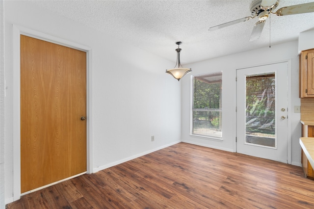 unfurnished dining area with a textured ceiling, wood-type flooring, and ceiling fan