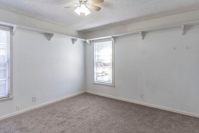 carpeted empty room with a wealth of natural light, ceiling fan, and a textured ceiling