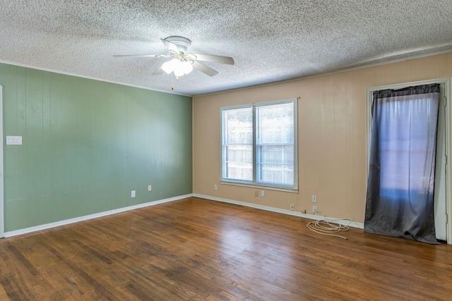 empty room with ceiling fan, a textured ceiling, wood walls, and dark wood-type flooring