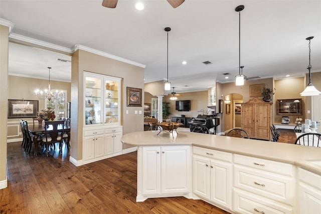 kitchen featuring ceiling fan with notable chandelier, crown molding, dark wood-type flooring, white cabinets, and hanging light fixtures