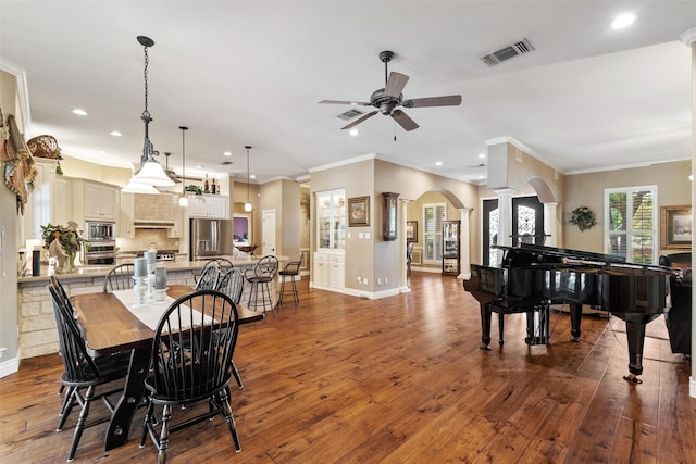 dining space with decorative columns, ceiling fan, ornamental molding, and hardwood / wood-style flooring