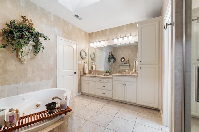 bathroom featuring tile patterned floors, vanity, tiled tub, and a skylight