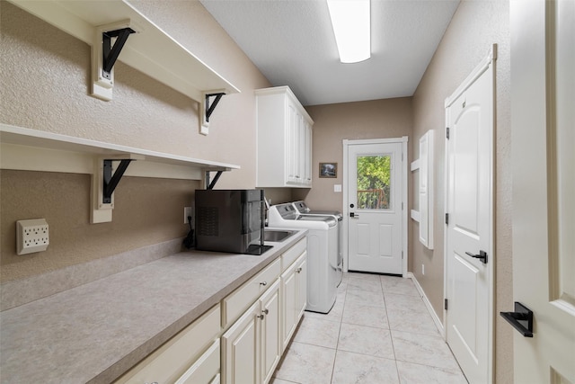 clothes washing area with cabinets, light tile patterned floors, and washing machine and dryer