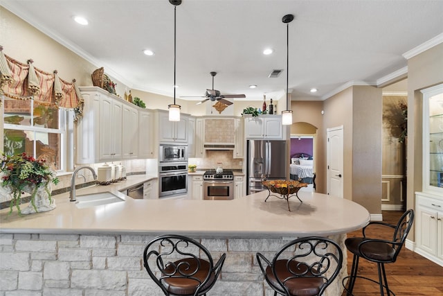 102 Ridge Ct, Glen Rose, TX 76043 - kitchen featuring appliances with stainless steel finishes, a breakfast bar area, a sink, a ceiling fan, and backsplash