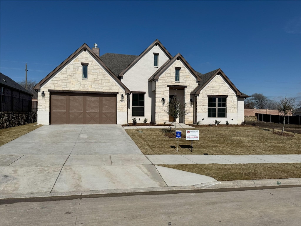 french provincial home featuring a garage and a front yard