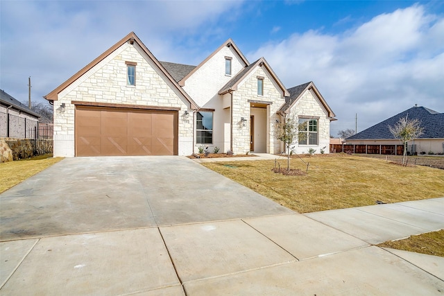 french country style house with a garage, concrete driveway, a front yard, and fence