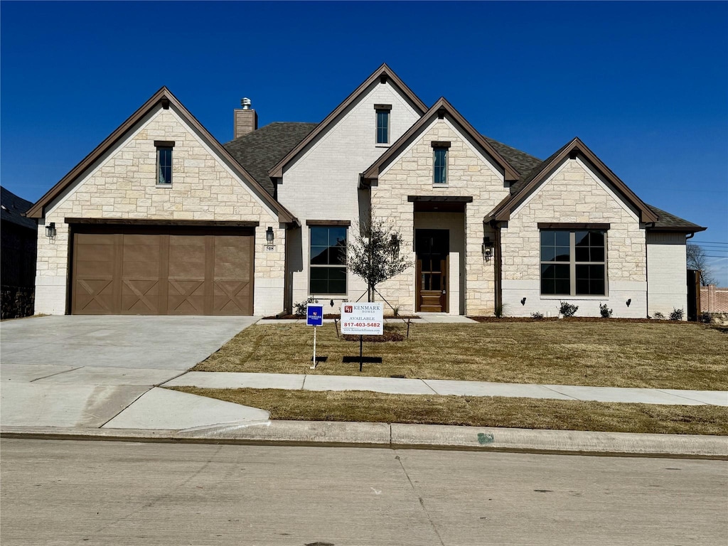 french country style house featuring a garage and a front yard