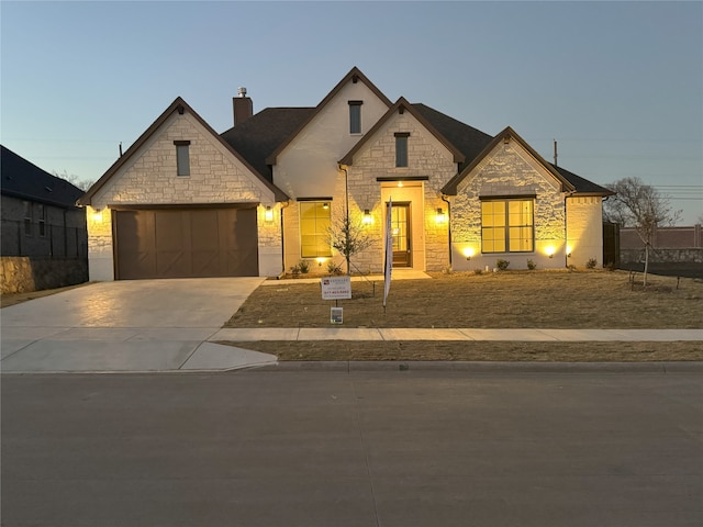 french country style house featuring driveway, an attached garage, and a chimney