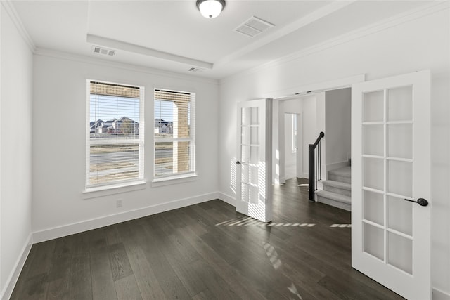 empty room featuring ornamental molding, dark hardwood / wood-style flooring, french doors, and a raised ceiling