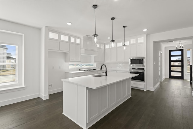 kitchen with hanging light fixtures, sink, white cabinets, a kitchen island with sink, and stainless steel appliances