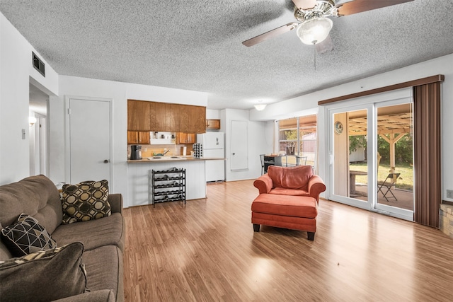 living room featuring a textured ceiling, light hardwood / wood-style floors, and ceiling fan