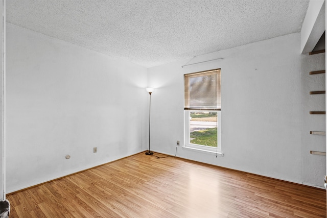 empty room with a textured ceiling and light hardwood / wood-style floors