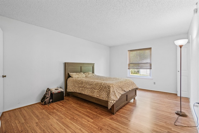 bedroom featuring a textured ceiling and light hardwood / wood-style floors