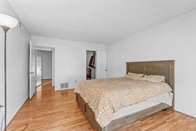 bedroom featuring a closet, light hardwood / wood-style floors, and a walk in closet