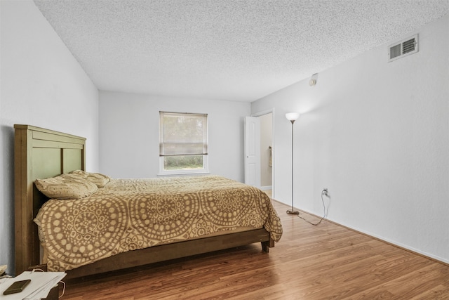 bedroom with a textured ceiling and hardwood / wood-style floors