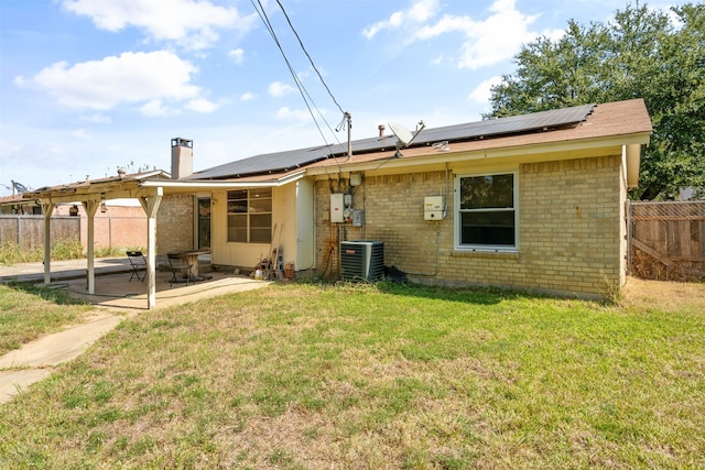 rear view of house with solar panels, cooling unit, a patio area, and a yard