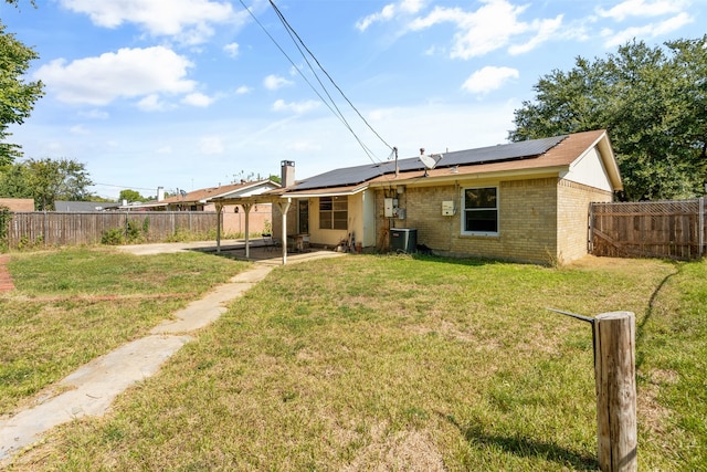 back of property featuring cooling unit, solar panels, a yard, and a patio