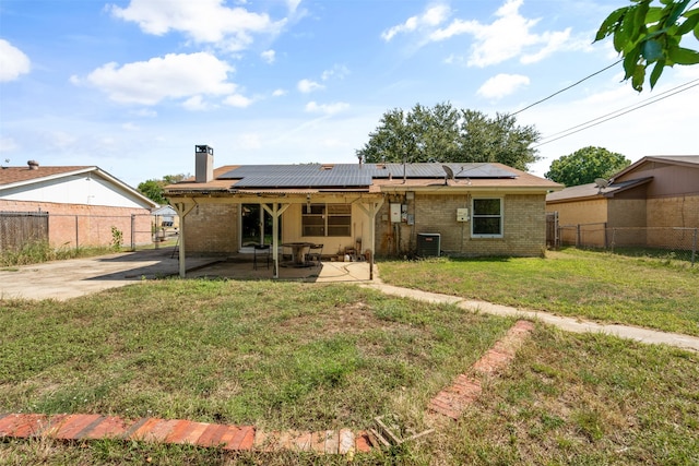 rear view of house with solar panels, a yard, a patio, and central AC