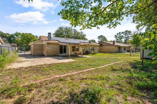 back of house with a yard, solar panels, and a patio area