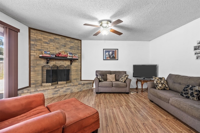 living room with ceiling fan, hardwood / wood-style flooring, a fireplace, and a textured ceiling