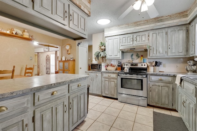 kitchen featuring ceiling fan, light tile patterned flooring, a textured ceiling, backsplash, and stainless steel appliances